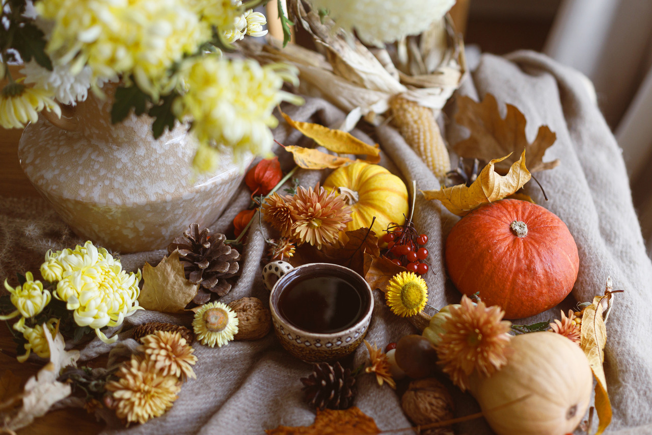Pumpkins and flowers sit on top of a tablecloth